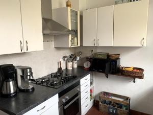 eine Küche mit weißen Schränken und einem Herd mit Backofen in der Unterkunft LA PETITE PRAIRIE 400m de la plage in Jard-sur-Mer