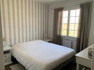 ein Schlafzimmer mit einem weißen Bett und einem Fenster in der Unterkunft LA PETITE PRAIRIE 400m de la plage in Jard-sur-Mer