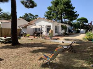 einen Garten mit einem Stuhl und einem Haus in der Unterkunft LA PETITE PRAIRIE 400m de la plage in Jard-sur-Mer