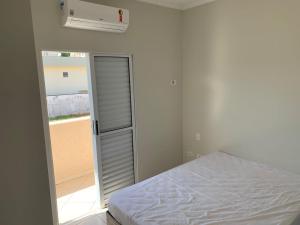 a white bedroom with a bed and a window at Apê Carla Valéria in Ubatuba