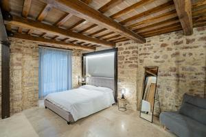 1 dormitorio con cama blanca y sofá en Anfihouse - Assisi Relais, en Asís