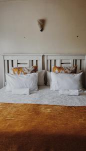 Una cama grande con almohadas blancas encima. en Lavender Lodge, en Mthatha
