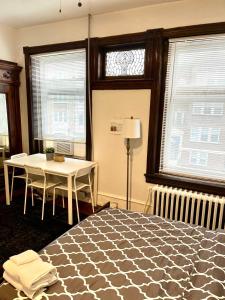 a bedroom with a bed and a table and windows at Legacy - Spring Garden University City in Philadelphia