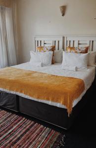 Una cama grande con una manta naranja. en Lavender Lodge, en Mthatha