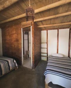 1 dormitorio con 2 camas en una habitación con paredes de madera en Naif habitaciones, en Máncora