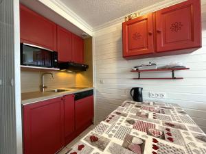 kuchnia z czerwonymi szafkami, zlewem i stołem w obiekcie Studio Les Menuires, 1 pièce, 4 personnes - FR-1-452-259 w Les Menuires