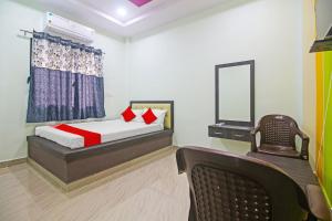 1 dormitorio con cama, silla y espejo en OYO Flagship Hotel Mh31, en Nagpur