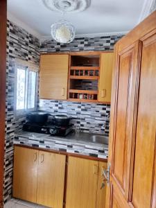 a kitchen with wooden cabinets and a tile wall at Residence Sighaka - Luxus VIP Apartment - WiFi, Gardien, Parking in Douala
