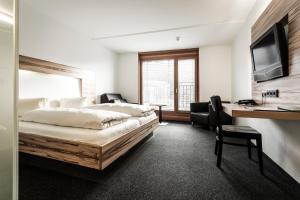 a bedroom with a bed and a desk with a computer at Hotel-Gasthof Löwen in Feldkirch