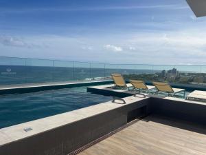 a swimming pool with chairs on top of a building at Stella Maris Vista de Cima in Salvador