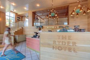 a woman walking past a counter in a restaurant at The Ryder Hotel in Charleston