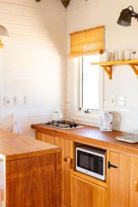 a kitchen with wooden cabinets and a microwave on a counter at Cabaña Sal de Mar in Punta Del Diablo