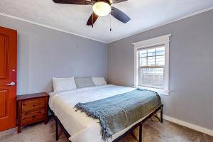 um quarto com uma cama, uma ventoinha de tecto e uma janela em Newberg Tropical Bungalow em Newberg