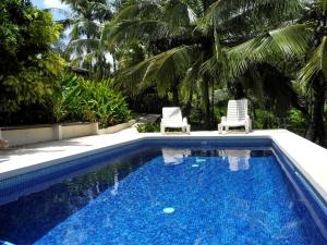 a swimming pool with two lawn chairs next to it at Casas Pelicano in Playa Junquillal
