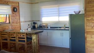 a kitchen with white cabinets and a refrigerator at Cabañas Flor de Conquil in Villarrica