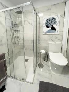 a white bathroom with a shower and a toilet at La Casita de Bonnie in La Tejita