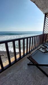 a chair on a balcony looking at the ocean at Sunset View 1-2 by Madriguera in La Libertad