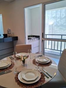 uma mesa de jantar com pratos e copos de vinho em Suíte confortável, churrasqueira e TV 55in em area nobre da cidade em Poços de Caldas