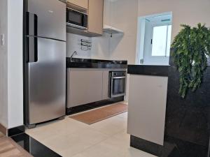 a kitchen with a stainless steel refrigerator and a sink at Suíte confortável, churrasqueira e TV 55in em area nobre da cidade in Poços de Caldas