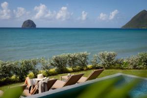 a group of people sitting in chairs by the ocean at Eden Roc Villas in Le Diamant