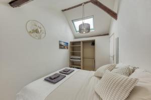 um quarto com uma cama branca e um relógio na parede em Le nid douillet - Proche Paris em Longjumeau