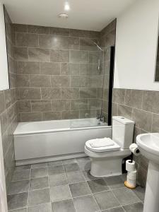 a bathroom with a tub and a toilet and a sink at 2 Ashbrook Margaret - luxury 2 bed ground floor in Oxford