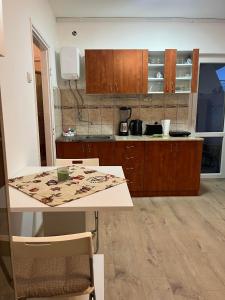 a kitchen with wooden cabinets and a table with chairs at Apartman LALA - Beograd, Surčin in Surčin