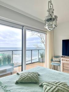 een slaapkamer met een bed en uitzicht op de oceaan bij Apartament Perłowy z BEZPOŚREDNIM WIDOKIEM na morze- Nadmorski Luksus Apartamenty in Ustronie Morskie