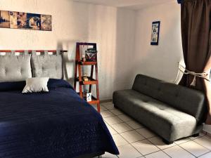 ein Schlafzimmer mit einem Bett und einem Sofa in der Unterkunft Posadas nido del tecolote in Guadalajara
