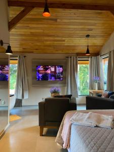 Pousada Maibe Amanhecer na Serra في غرامادو: غرفة معيشة مع سرير وتلفزيون بشاشة مسطحة