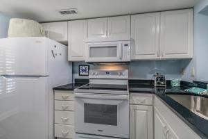 a kitchen with white cabinets and a stove and microwave at Ocean Front D-Building - POOL ACCESS AND OCEAN VIEWS!!! in Harbor Island