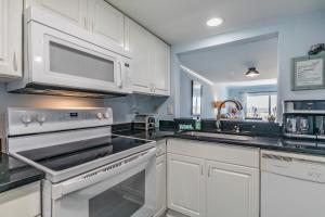 a kitchen with white cabinets and white appliances at Ocean Front D-Building - POOL ACCESS AND OCEAN VIEWS!!! in Harbor Island