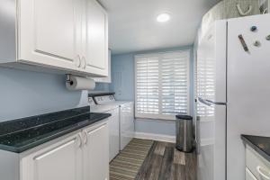 a kitchen with white cabinets and a refrigerator at Ocean Front D-Building - POOL ACCESS AND OCEAN VIEWS!!! in Harbor Island