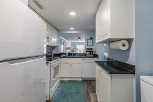 a kitchen with white cabinets and a sink at Ocean Front D-Building - POOL ACCESS AND OCEAN VIEWS!!! in Harbor Island