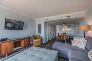 a living room with a couch and a tv at Ocean Front D-Building - POOL ACCESS AND OCEAN VIEWS!!! in Harbor Island