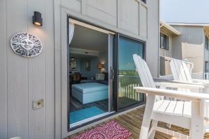 a balcony with two white chairs and a patio door at Ocean Front D-Building - POOL ACCESS AND OCEAN VIEWS!!! in Harbor Island