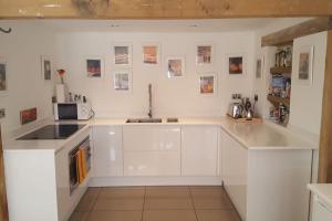 a white kitchen with a sink and a microwave at Prestwick Oak - Sleeps 10 - Rural Oak Frame Barns in Chiddingfold