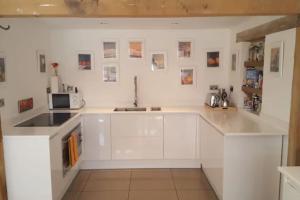 uma cozinha branca com um lavatório e um micro-ondas em Prestwick Oak - Sleeps 10 - Rural Oak Frame Barns em Chiddingfold