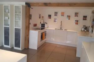 uma cozinha com armários brancos e uma bancada em Prestwick Oak - Sleeps 10 - Rural Oak Frame Barns em Chiddingfold
