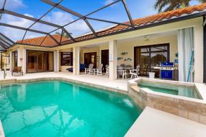 a house with a swimming pool and a patio at Driftwood Dreams in Marco Island