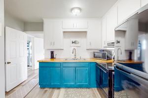 una cocina con armarios azules y blancos y fregadero en Summer Blues Bungalow, en Aransas Pass
