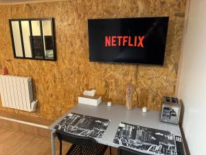 einen Tisch mit einem Netflix-Schild an der Wand in der Unterkunft Studio proche forêt in Montmorency