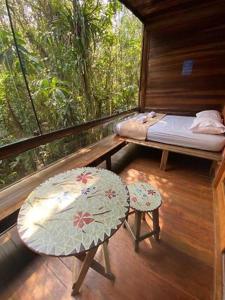 Habitación con cama y mesa en el balcón. en Condomínio Mata Azul, en São Sebastião