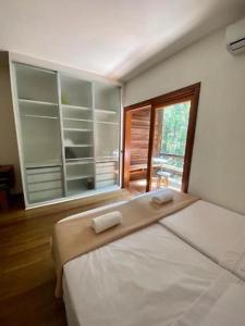 Un dormitorio con una cama grande con ventana. en Condomínio Mata Azul, en São Sebastião