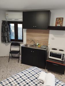 a kitchen with a bed and a sink and a microwave at Ξενώνας museum ισόγειο στο Ελληνικό Ιωαννίνων in Kalentzi