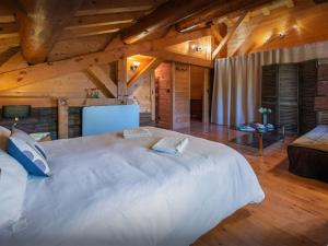 a large white bed in a room with wooden ceilings at Chalet Capieu - Le Barn - OVO Network in Manigod