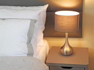 um candeeiro numa mesa de cabeceira ao lado de uma cama em A Home from Home - Leamington Spa em Leamington Spa