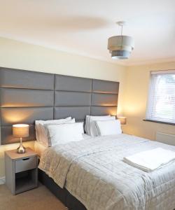 a bedroom with a large bed with a gray headboard at A Home from Home - Leamington Spa in Leamington Spa