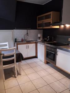 uma cozinha com armários brancos, uma mesa e um fogão em Superbe logement à proximité du centre et du Kirchberg em Luxemburgo