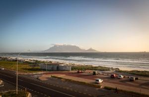 a road next to the ocean with a mountain in the background at Sea Spray A308 by Host Agents in Bloubergstrand